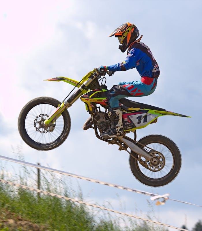 Rider performing an airborne trick on a motocross bike, showcasing speed and agility.